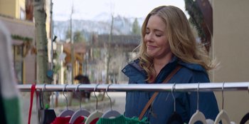 Movie still from “I Believe in Santa” (2022), directed by Alex Ranarivelo – A woman standing in front of a rack of clothes; Medium shot, Over the shoulder angle