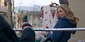 Movie still from “I Believe in Santa” (2022), directed by Alex Ranarivelo – A woman is holding onto a christmas sweater; Medium shot, Over the shoulder angle