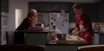 Movie still from “I Believe in Santa” (2022), directed by Alex Ranarivelo – A man and a woman in a kitchen preparing food; Medium shot, Over the shoulder angle