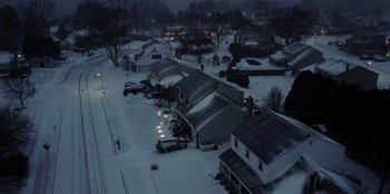 Movie still from “I Believe in Santa” (2022), directed by Alex Ranarivelo – An aerial view of a residential neighborhood covered in snow at night; Extreme Wide shot, High angle