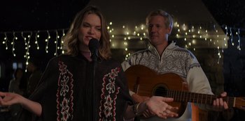 Movie still from “I Believe in Santa” (2022), directed by Alex Ranarivelo – A man and a woman singing into a microphone; Medium shot, Over the shoulder angle