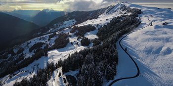 Movie still from “I Believe in Santa” (2022), directed by Alex Ranarivelo – An aerial view of a snow covered slope with trees; Extreme Wide shot, High angle