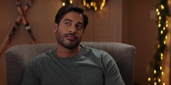 Movie still from “I Believe in Santa” (2022), directed by Alex Ranarivelo – A person sitting on a couch; Close Up shot, Over the shoulder angle