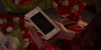 Movie still from “I Believe in Santa” (2022), directed by Alex Ranarivelo – A person holding an iphone in their hands; Extreme Close Up shot, High angle