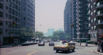 Movie still from “I Spit on Your Grave” (1978), directed by Meir Zarchi – Cars driving down a street in a city; Extreme Wide shot, High angle