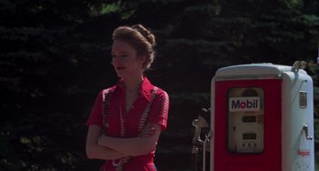 Movie still from “I Spit on Your Grave” (1978), directed by Meir Zarchi – A woman standing next to an old gas pump; Medium shot, Over the shoulder angle