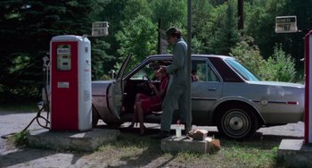 Movie still from “I Spit on Your Grave” (1978), directed by Meir Zarchi – A man and a woman standing next to an old car; Wide shot, Low angle
