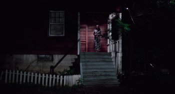 Movie still from “I Spit on Your Grave” (1978), directed by Meir Zarchi – A person standing on the steps of a house at night; Extreme Wide shot, Low angle