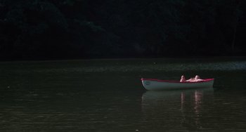 Movie still from “I Spit on Your Grave” (1978), directed by Meir Zarchi – A boat floating on top of a body of water at night; Extreme Wide shot, High angle