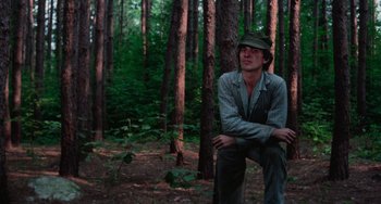 Movie still from “I Spit on Your Grave” (1978), directed by Meir Zarchi – A man sitting in the middle of a forest; Medium shot, Low angle