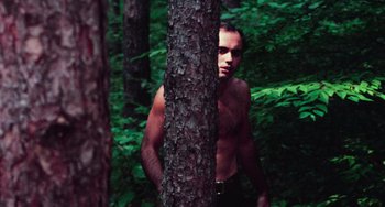 Movie still from “I Spit on Your Grave” (1978), directed by Meir Zarchi – A man standing next to a tree in the woods; Medium shot, Low angle