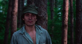 Movie still from “I Spit on Your Grave” (1978), directed by Meir Zarchi – A man wearing a hat standing next to a tree; Close Up shot, Low angle