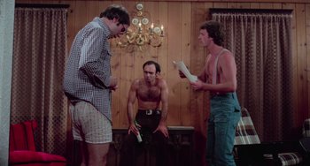 Movie still from “I Spit on Your Grave” (1978), directed by Meir Zarchi – A group of men standing in front of each other in a living room; Medium shot, Low angle