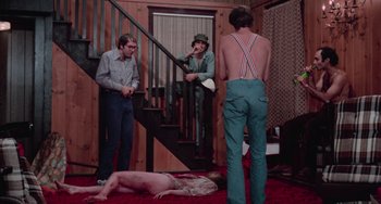 Movie still from “I Spit on Your Grave” (1978), directed by Meir Zarchi – A group of men standing around a man laying on the ground; Wide shot, High angle