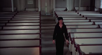 Movie still from “I Spit on Your Grave” (1978), directed by Meir Zarchi – A woman in a long black dress walking in a room; Wide shot, High angle