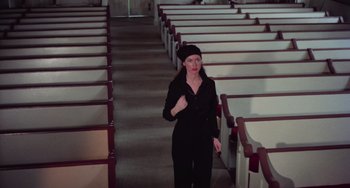 Movie still from “I Spit on Your Grave” (1978), directed by Meir Zarchi – A woman in all black standing next to a row of pedestals; Medium shot, High angle