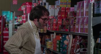 Movie still from “I Spit on Your Grave” (1978), directed by Meir Zarchi – A man looking down at a shelf in a grocery store; Medium shot, Low angle