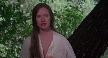 Movie still from “I Spit on Your Grave” (1978), directed by Meir Zarchi – A woman in a white shirt standing next to a tree; Close Up shot, Over the shoulder angle