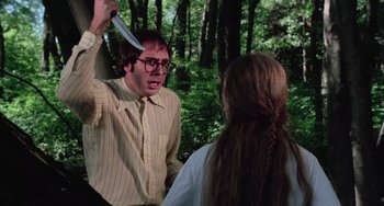 Movie still from “I Spit on Your Grave” (1978), directed by Meir Zarchi – A man with a knife in his face and a woman with a braid in a forest; Medium shot, Over the shoulder angle