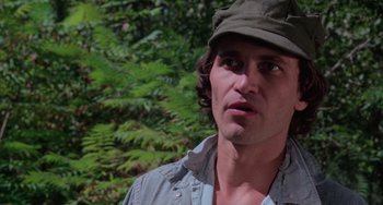 Movie still from “I Spit on Your Grave” (1978), directed by Meir Zarchi – A person wearing a hat near a forest; Close Up shot, Low angle