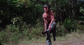 Movie still from “I Spit on Your Grave” (1978), directed by Meir Zarchi – A shirtless man holding a baseball bat in the woods; Wide shot, Low angle