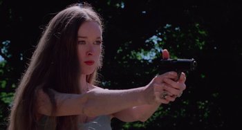 Movie still from “I Spit on Your Grave” (1978), directed by Meir Zarchi – A beautiful young lady holding a gun in her hand; Close Up shot, Low angle