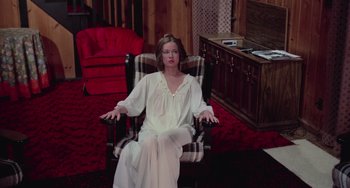 Movie still from “I Spit on Your Grave” (1978), directed by Meir Zarchi – A woman sitting in a chair wearing a nightgown; Wide shot, High angle