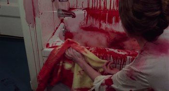 Movie still from “I Spit on Your Grave” (1978), directed by Meir Zarchi – A person in a bathroom covered in red paint; Medium shot, High angle
