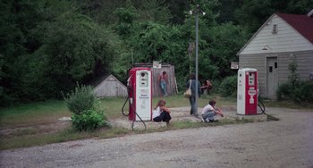 Movie still from “I Spit on Your Grave” (1978), directed by Meir Zarchi – A group of people standing around an old gas pump; Extreme Wide shot, High angle