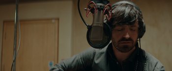 A man with a beard is recording a song in a recording studio