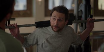 Movie still from “I Want You Back” (2022), directed by Jason Orley – A person holding a barbell on their shoulder; Medium shot, Over the shoulder angle