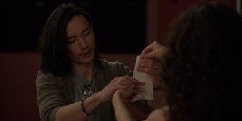 Movie still from “I Want You Back” (2022), directed by Jason Orley – A man with long black hair is holding a paper towel; Close Up shot, Over the shoulder angle