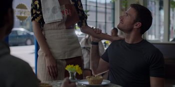 Movie still from “I Want You Back” (2022), directed by Jason Orley – A man holding a woman's hand in front of a plate of food; Medium shot, Over the shoulder angle