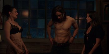 Movie still from “I Want You Back” (2022), directed by Jason Orley – A man with long black hair is standing in front of a brick wall; Medium shot, High angle