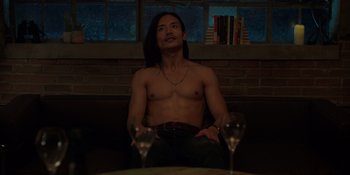 Movie still from “I Want You Back” (2022), directed by Jason Orley – A man sitting on a couch next to two wine glasses; Medium shot, High angle