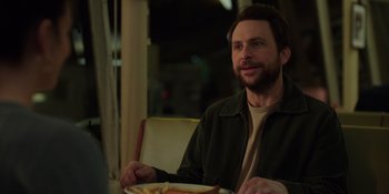 Movie still from “I Want You Back” (2022), directed by Jason Orley – A man sitting in front of a plate of food; Medium shot, Over the shoulder angle
