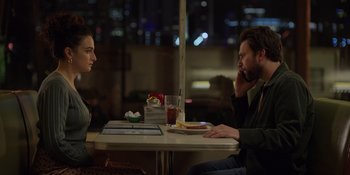 Movie still from “I Want You Back” (2022), directed by Jason Orley – A man and a woman are sitting at a table; Medium shot, Over the shoulder angle