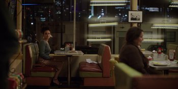 Movie still from “I Want You Back” (2022), directed by Jason Orley – A woman sitting at a table in front of a window; Wide shot, Over the shoulder angle