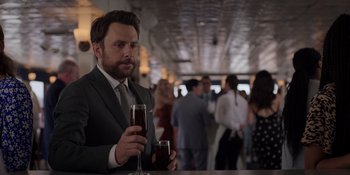 Movie still from “I Want You Back” (2022), directed by Jason Orley – A man in a suit and tie holding a glass of wine; Close Up shot, Over the shoulder angle