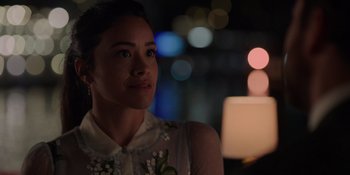 Movie still from “I Want You Back” (2022), directed by Jason Orley – A woman in a white dress is standing in front of a candle; Close Up shot, Over the shoulder angle