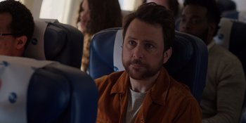 Movie still from “I Want You Back” (2022), directed by Jason Orley – A man sitting on a seat on an airplane; Close Up shot, Over the shoulder angle