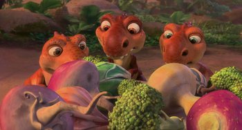 Movie still from “Ice Age: Dawn of the Dinosaurs” (2009), directed by Michael Thurmeier – A group of three dinosaurs standing next to a pile of broccoli; Wide shot, High angle