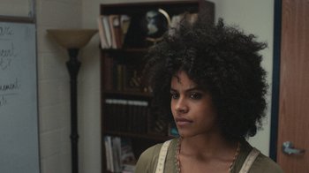 Movie still from “Atlanta” (2016), created by Donald Glover – A woman with a very large afro is standing in front of a bookcase; Close Up shot, Over the shoulder angle