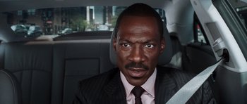 Movie still from “Imagine That” (2009), directed by Karey Kirkpatrick – A man wearing a suit and tie sitting in the back of a car; Close Up shot, Over the shoulder angle
