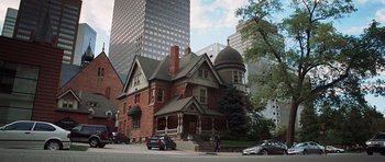 Movie still from “Imagine That” (2009), directed by Karey Kirkpatrick – An old style house with a turreted roof in the middle of a city; Extreme Wide shot, High angle