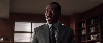 Movie still from “Imagine That” (2009), directed by Karey Kirkpatrick – A man wearing a suit and tie in front of a window; Close Up shot, Low angle