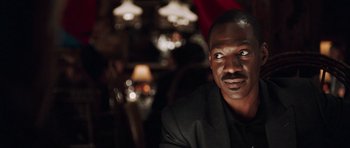 Movie still from “Imagine That” (2009), directed by Karey Kirkpatrick – A man in a suit sitting in front of some lights; Close Up shot, Over the shoulder angle