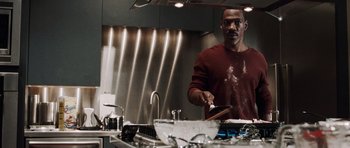 Movie still from “Imagine That” (2009), directed by Karey Kirkpatrick – A man in a kitchen preparing food on a cutting board; Medium shot, High angle