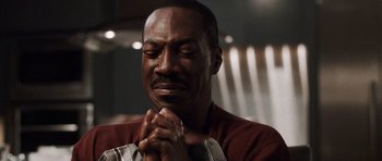 Movie still from “Imagine That” (2009), directed by Karey Kirkpatrick – An older black man with his hands clasped in prayer; Close Up shot, Low angle