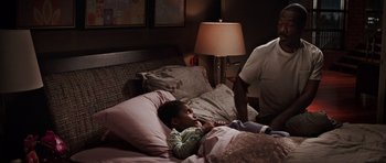Movie still from “Imagine That” (2009), directed by Karey Kirkpatrick – A child laying in a bed next to an older man; Medium shot, Over the shoulder angle
